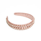 A light pink headband with fabric ruffles and multiple square silver crystals.