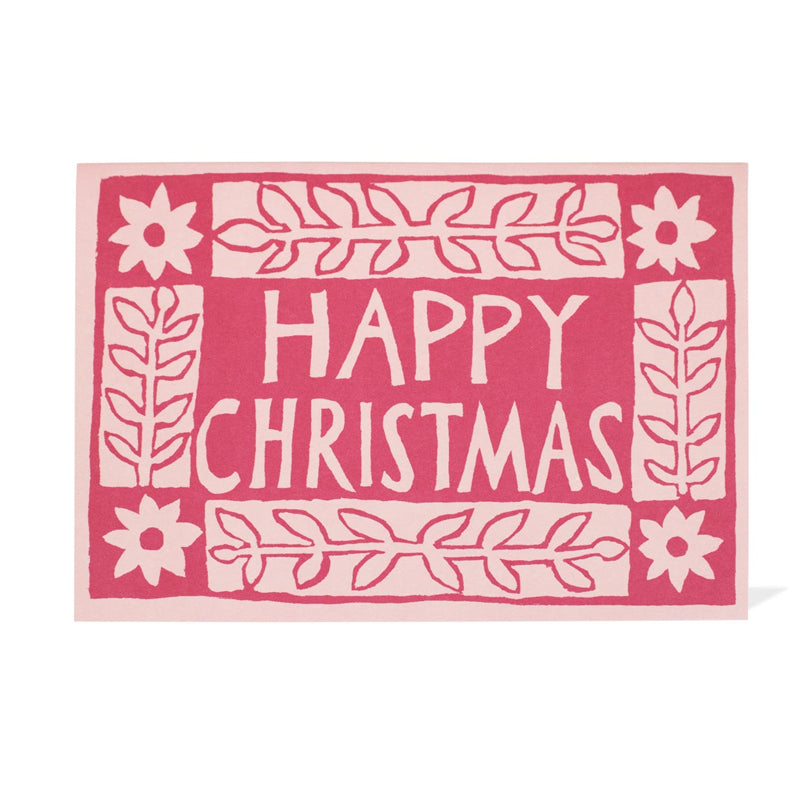 Light pink and magenta card with flower designs in blocks with the words "happy christmas" on it. 