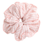 Pink and white striped hair scrunchie against a white background.