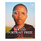 Book cover of 'Taylor Wessing Photo Portrait Prize 25' featuring a young person with glasses against a blue sky.