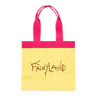 A yellow canvas tote bag with a hot pink top border and matching pink handles, featuring the word 'FAIRYLAND' embroidered in brown across the front.