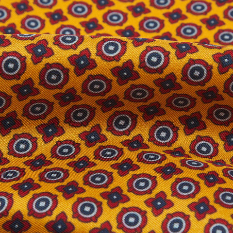 A close up of the yellow pocket square showing the small blue and red designs. 