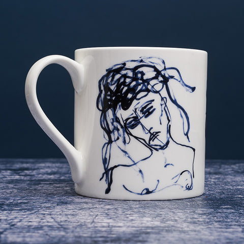 White ceramic mug with dark blue ink design of a woman. 