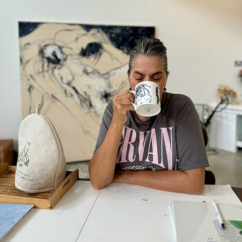 Photograph of Tracey Emin in her studio drinking from a mug.