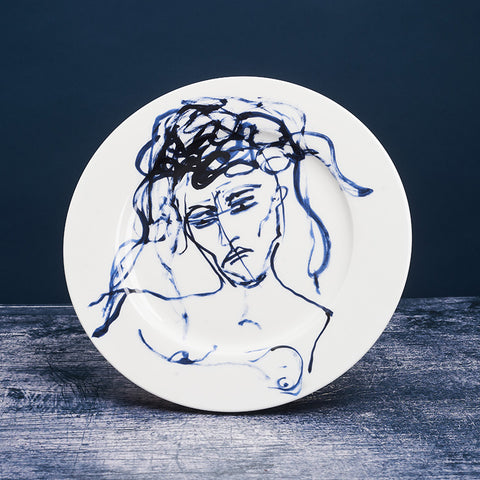 White ceramic plate with dark blue ink design of a woman.