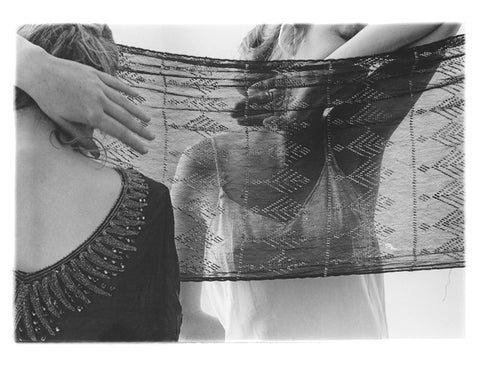 Photographic postcard of a woman's reflection behind a scarf.