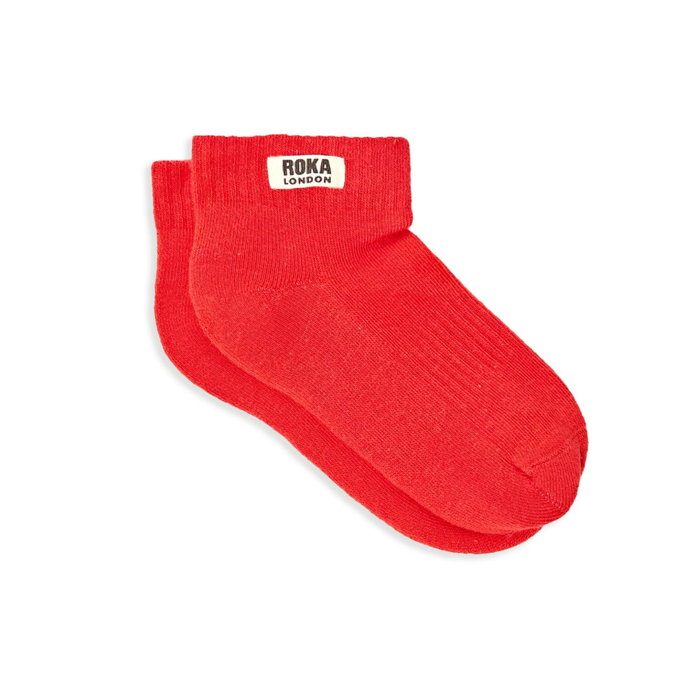 A pair of ribbed red socks with white label and the words roka london against a white background.