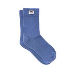 A pair of medium blue ribbed crew socks with a white rectangular brand label on the cuff, displayed on a clean white background.