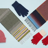 A light blue background with several winter warmers, like gloves, hats and scarves.