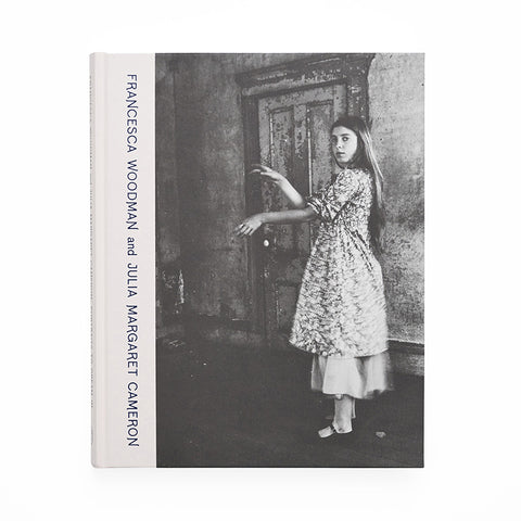 Book cover featuring a light pink spine and black and white photograph of a young girl in a dress in front of a door. 