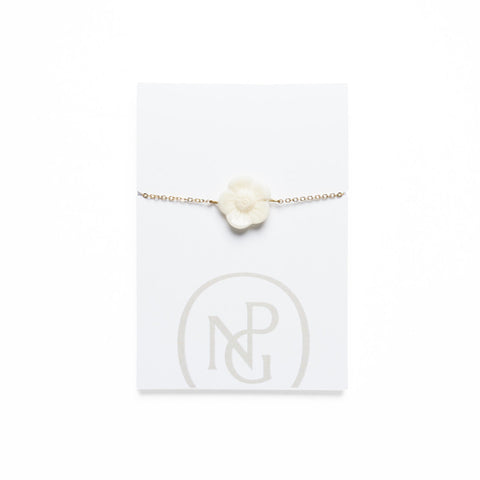 Carved floral pendant on a gold chain bracelet against National Portrait Gallery card packaging.