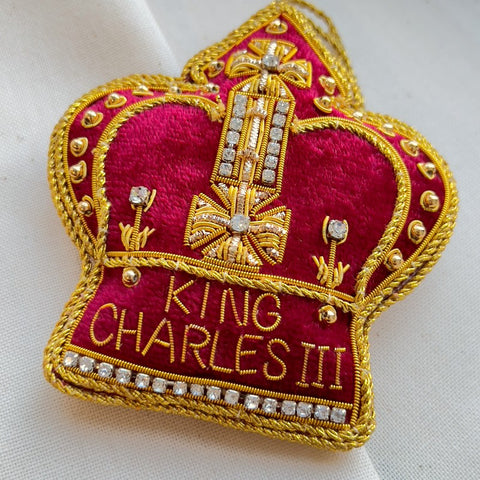 Red velvet crown shaped decoration with gold embroidered text which reads 'King Charles III' and diamantes.
